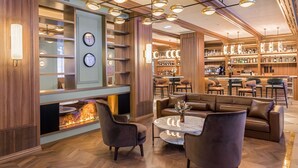 A modern lounge area with leather sofas, a marble coffee table, and a bar with shelves of bottles. - Canfranc Estación, A Royal Hideaway Hotel - Gran Lujo (Canfranc)