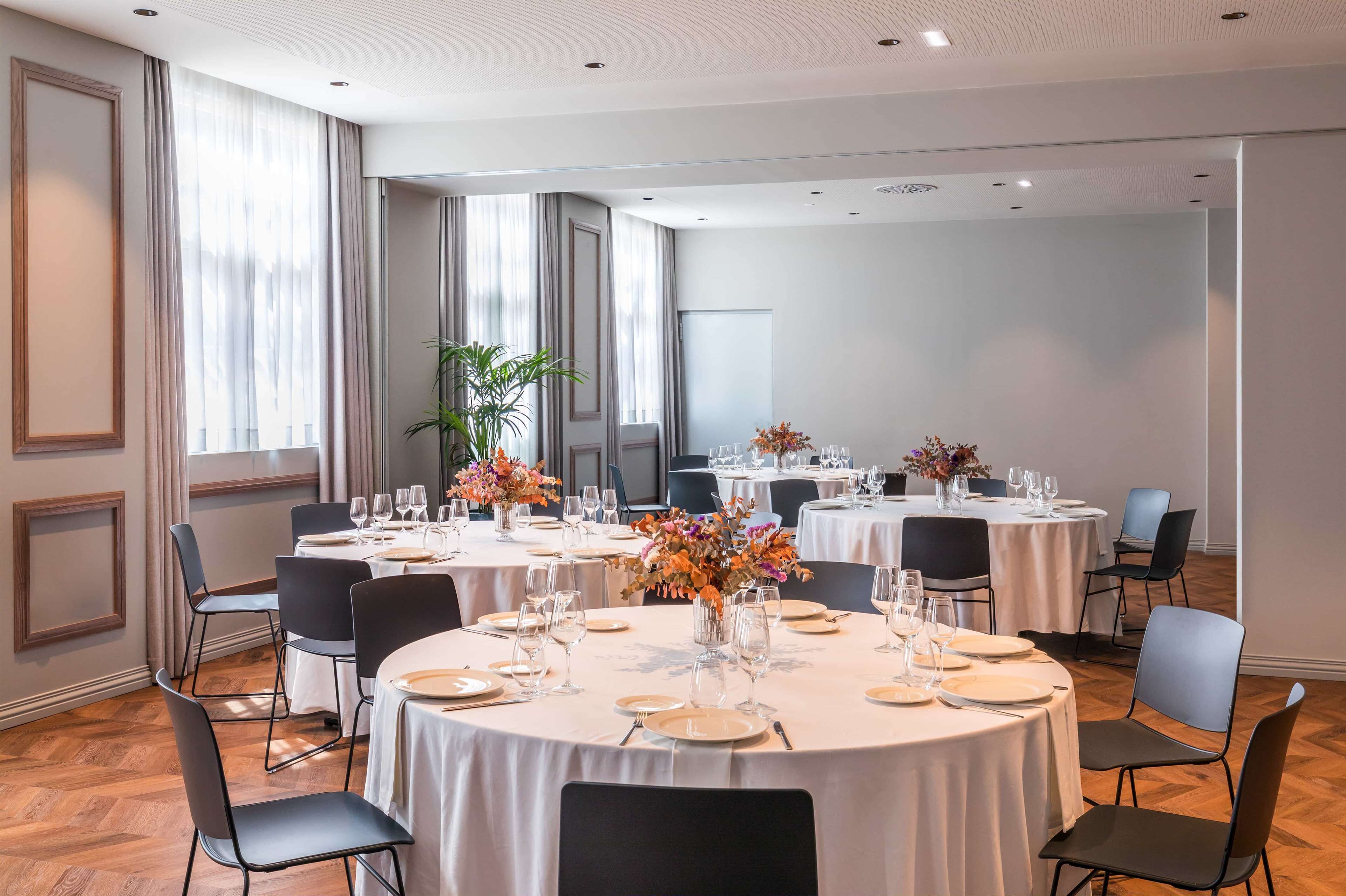 A conference room with round tables, chairs, and floral centerpieces.