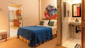 A bedroom with a bed, a bathroom with a sink, and a view of the kitchen. - Eco Park Inn (Crown Point)