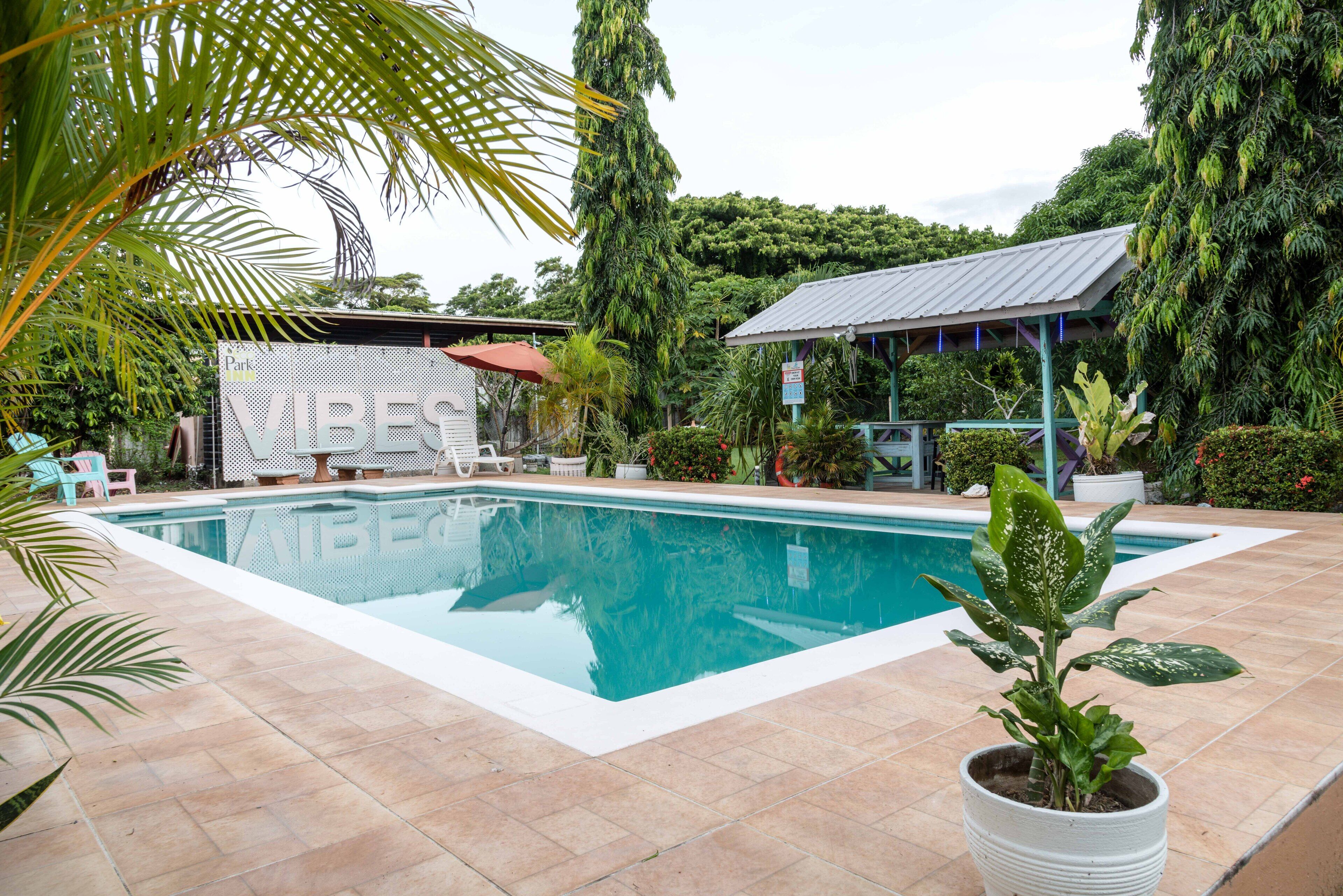 A swimming pool surrounded by potted plants and a covered seating area.