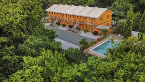 An orange building with a pool, surrounded by dense greenery. - Eco Park Inn (Crown Point)