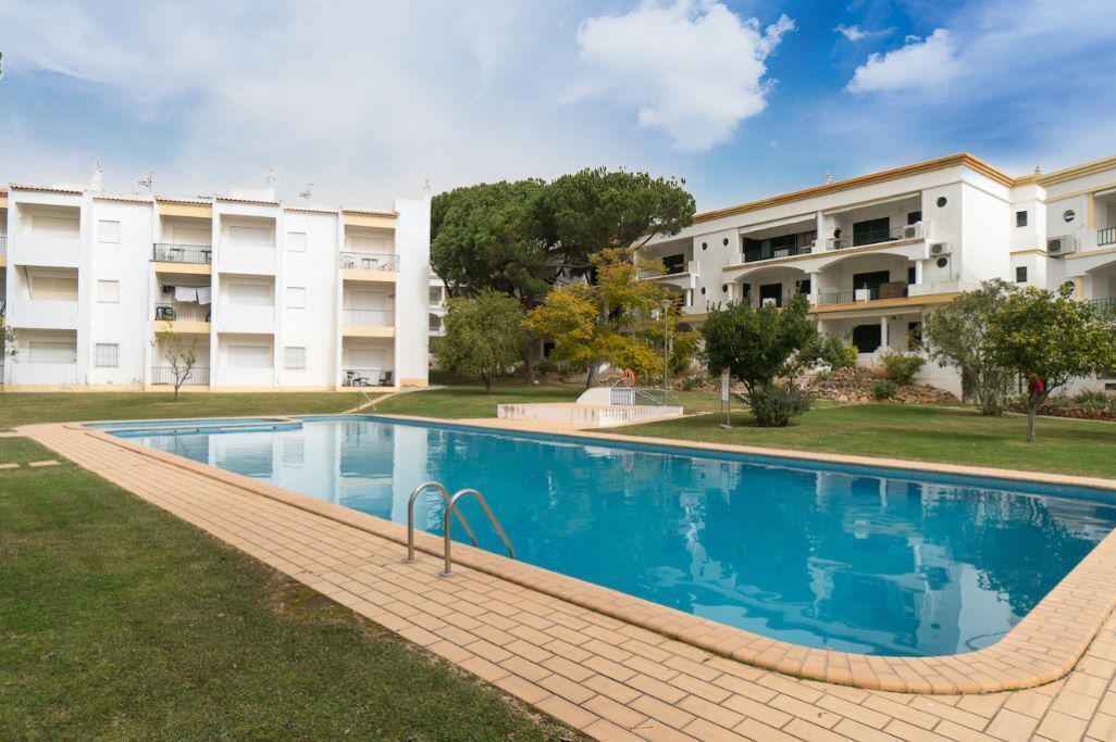 Une piscine dotée d’une terrasse carrelée, entourée d’une pelouse et d’arbres.