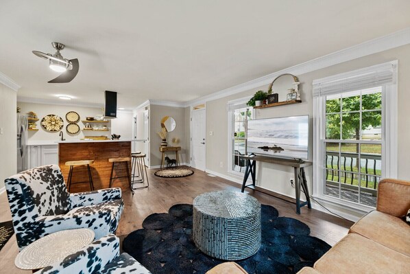A spacious living room with a large window, a kitchen area, and a dining space.