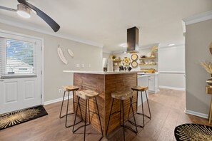 A modern kitchen with a central island, bar stools, and a built-in stove. - Charming House in Downtown Raleigh- Walking Distance (Raleigh)