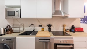 A modern kitchen with white cabinets, a stainless steel microwave, a sink, a toaster, and a dishwasher. - 1)The Heart Of The City, Sol, By MoNARO (Madrid)