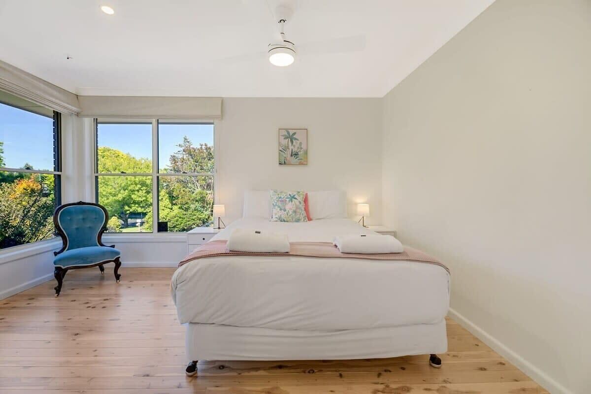 A bedroom with a large bed, a chair, and a view through a window.