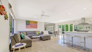 A modern living room with a sofa, coffee table, and a dining area with chairs and a bar.