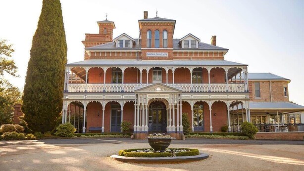 A large, historic building with a central entrance, arched windows, and a symmetrical facade.