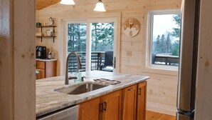 Une cuisine rustique, aménagée dans une cabane en bois, avec un évier, des placards et un réfrigérateur.