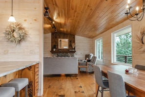 Een houten hut van binnen met een eethoek, bar en zitplaatsen.
