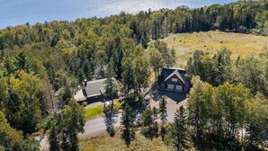 Une maison entourée d’une forêt dense, avec vue sur une vaste étendue d’eau.