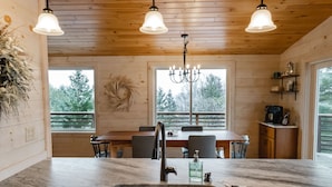Une cuisine dotée d’un plan de travail en marbre, d’un robinet moderne et de luminaires suspendus. On y trouve également un coin repas avec une table et des chaises en bois.