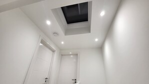 A modern, white interior with a skylight and recessed lighting.
