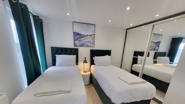A hotel room with two beds, a large mirror, and artwork on the wall.