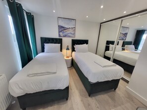 Habitación de hotel con dos camas, un espejo grande y obras de arte en la pared.