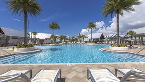 A pool area with lounge chairs, palm trees, and a clear blue sky.