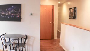 A room with a dining table and chairs, a wooden door, and a painting on the wall. - Carey Way Quarters-Stylish 3BR Loft-Prime Location (Pittsburgh)