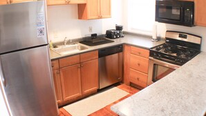 A modern kitchen with wooden cabinets, stainless steel appliances, and a granite countertop. - Carey Way Quarters-Stylish 3BR Loft-Prime Location (Pittsburgh)