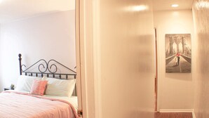 A bedroom with a bed, a door, and a painting on the wall. - Carey Way Quarters-Stylish 3BR Loft-Prime Location (Pittsburgh)