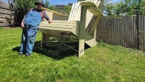Eine Person steht neben einer Holzhütte im Garten.