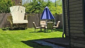 Ein Garten mit einer Holzterrasse, einem blauen Sonnenschirm und Gartenmöbeln.