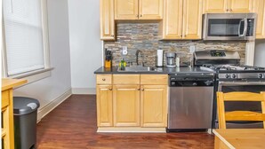 A kitchen with wooden cabinets, a stainless steel stove, a microwave, and a dishwasher. - Charming 1-BR Apartment Near Amazing Views in Pittsburgh! (Pittsburgh)