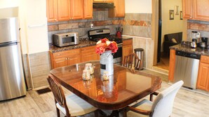 Una cocina moderna con armarios de madera, encimera de granito, electrodomésticos de acero inoxidable y una mesa de comedor con sillas.