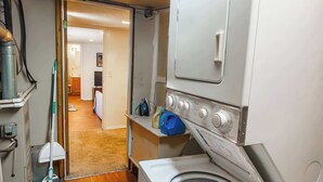 Ein Waschraum mit einer Waschmaschine und einem Trockner, einem Mop und einer Kost.
