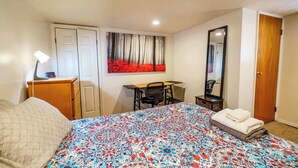 Ein Hotelzimmer mit Bett, Schreibtisch, Stuhl, Kleiderschrank und Spiegel.