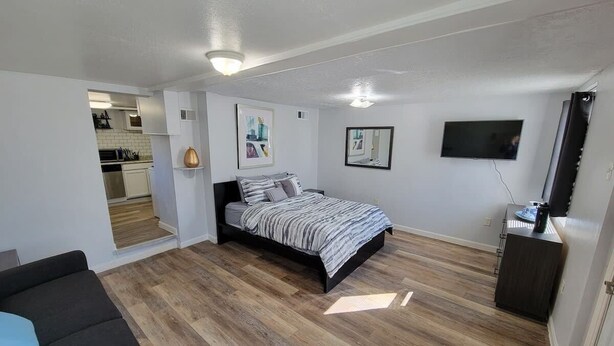 A compact bedroom with a bed, a TV, and a small desk. - California Ave Quarters - Modern 1BR - EZ Parking (Pittsburgh)