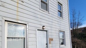 A two-story house with a white exterior, a front door, and a mailbox. - California Ave Quarters - Modern 1BR - EZ Parking (Pittsburgh)