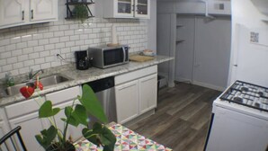 A compact kitchen with white cabinets, a microwave, a coffee maker, and a gas stove. - California Ave Quarters - Modern 1BR - EZ Parking (Pittsburgh)