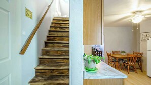 Un escalier avec des marches en bois et un panneau d’avertissement indiquant une faible hauteur sous plafond.