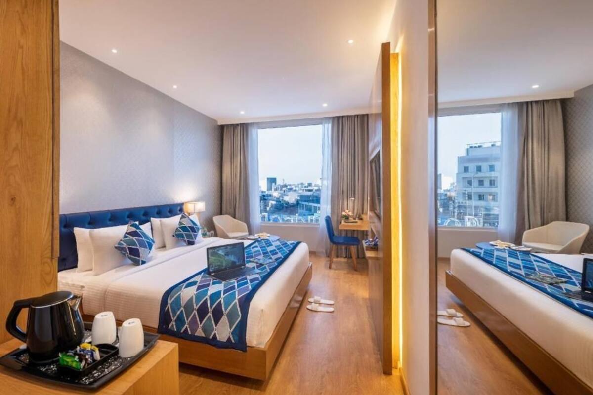 Een hotelkamer met een bed, bureau, stoel en uitzicht op de stad.