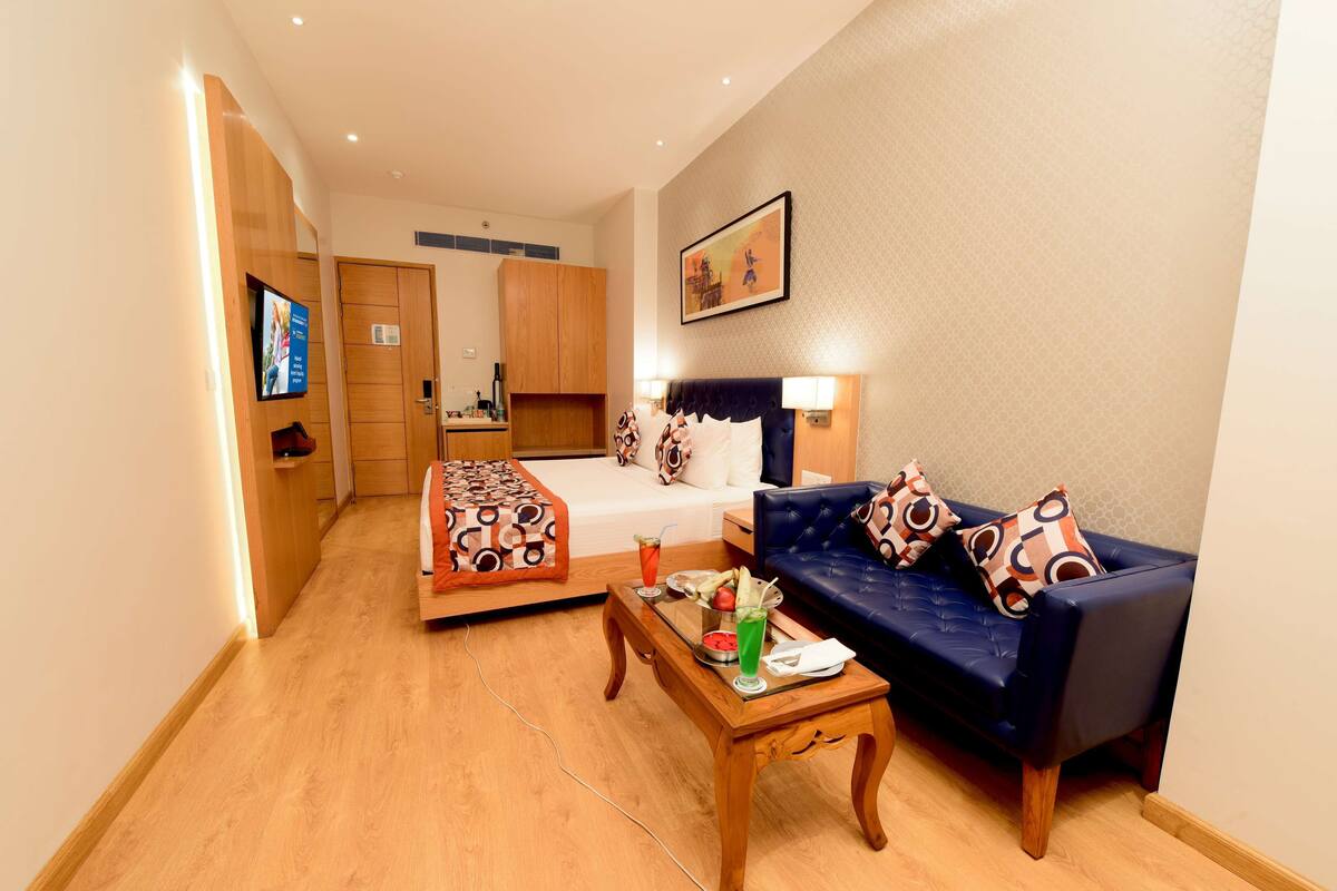 Een hotelkamer met een bed, een bank, een houten salontafel en een televisie.