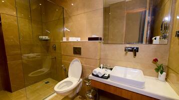 A modern bathroom with a glass-enclosed shower, a white toilet, and a vanity with a sink and mirror.