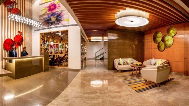 Een moderne lobby met een receptiebalie, een zithoek en een trap.