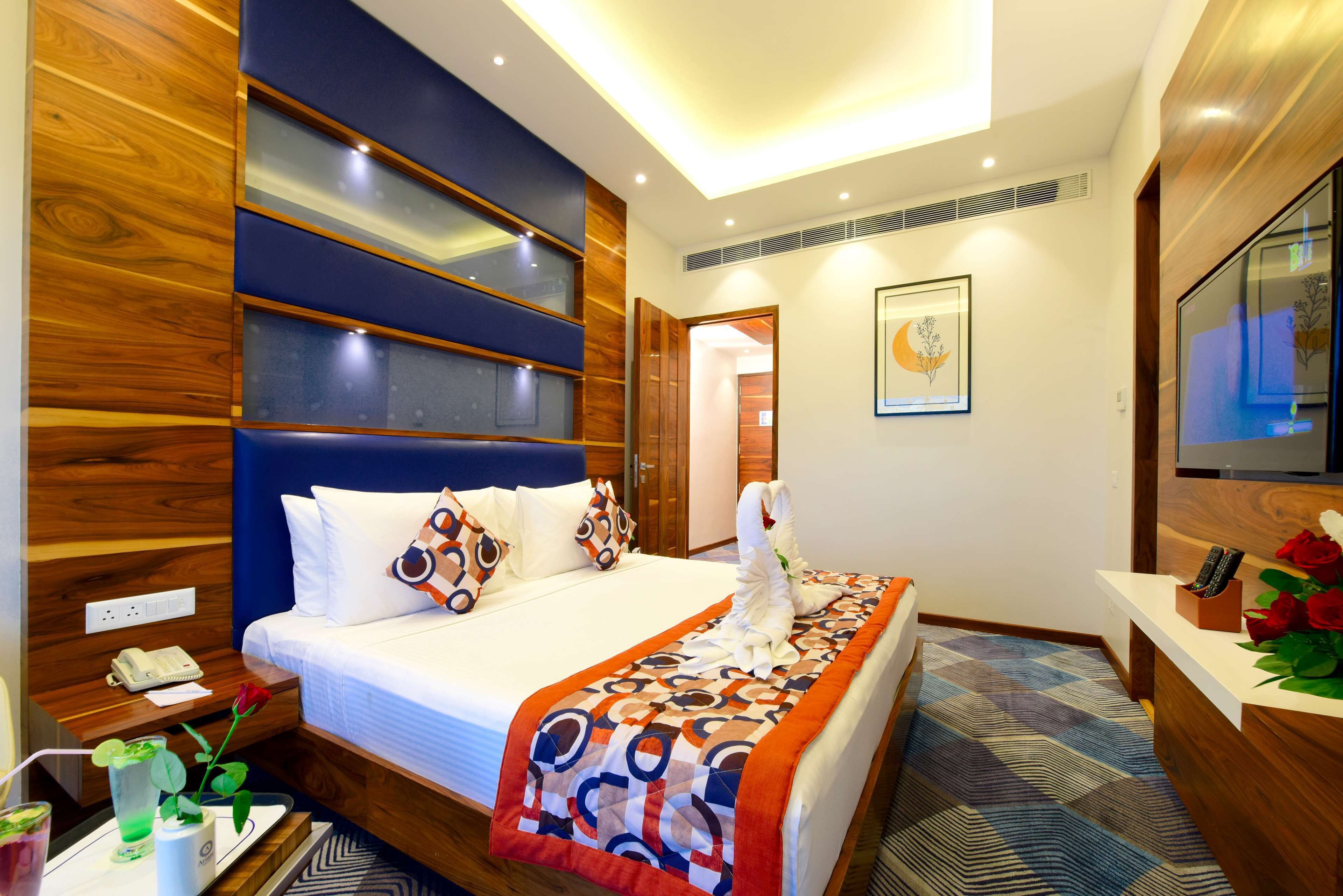 A hotel room with a large bed, wooden paneling, a desk with a telephone, and a bathroom visible through an open door.