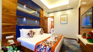 A hotel room with a large bed, wooden paneling, a desk with a telephone, and a bathroom visible through an open door.