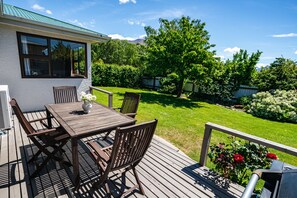 A wooden deck with a table and chairs, a potted plant, and a barbecue grill.