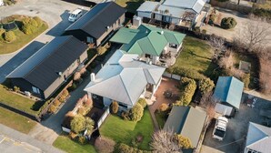 An aerial view of a residential area with multiple houses, each featuring distinct roof designs and surrounded by well-maintained lawns and gardens. - Downtown Delight - Wanaka Holiday Home (Wanaka)