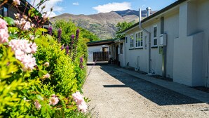 A gravel driveway leading to a building with a white exterior and a mountain backdrop. - Downtown Delight - Wanaka Holiday Home (Wanaka)