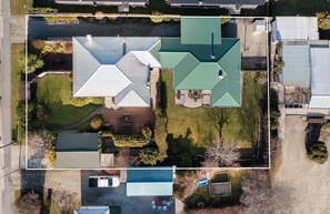 An aerial view of a residential area with multiple houses, green lawns, and a small parking area.