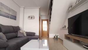A living room with a grey sofa, white coffee table, and a TV on a wooden stand. - Villa Terreros 365 days of sunshine (Pulpí)
