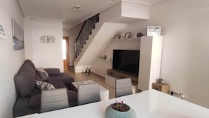 A modern living room with a sofa, coffee table, and TV. There is a staircase leading to another level. - Villa Terreros 365 days of sunshine (Pulpí)