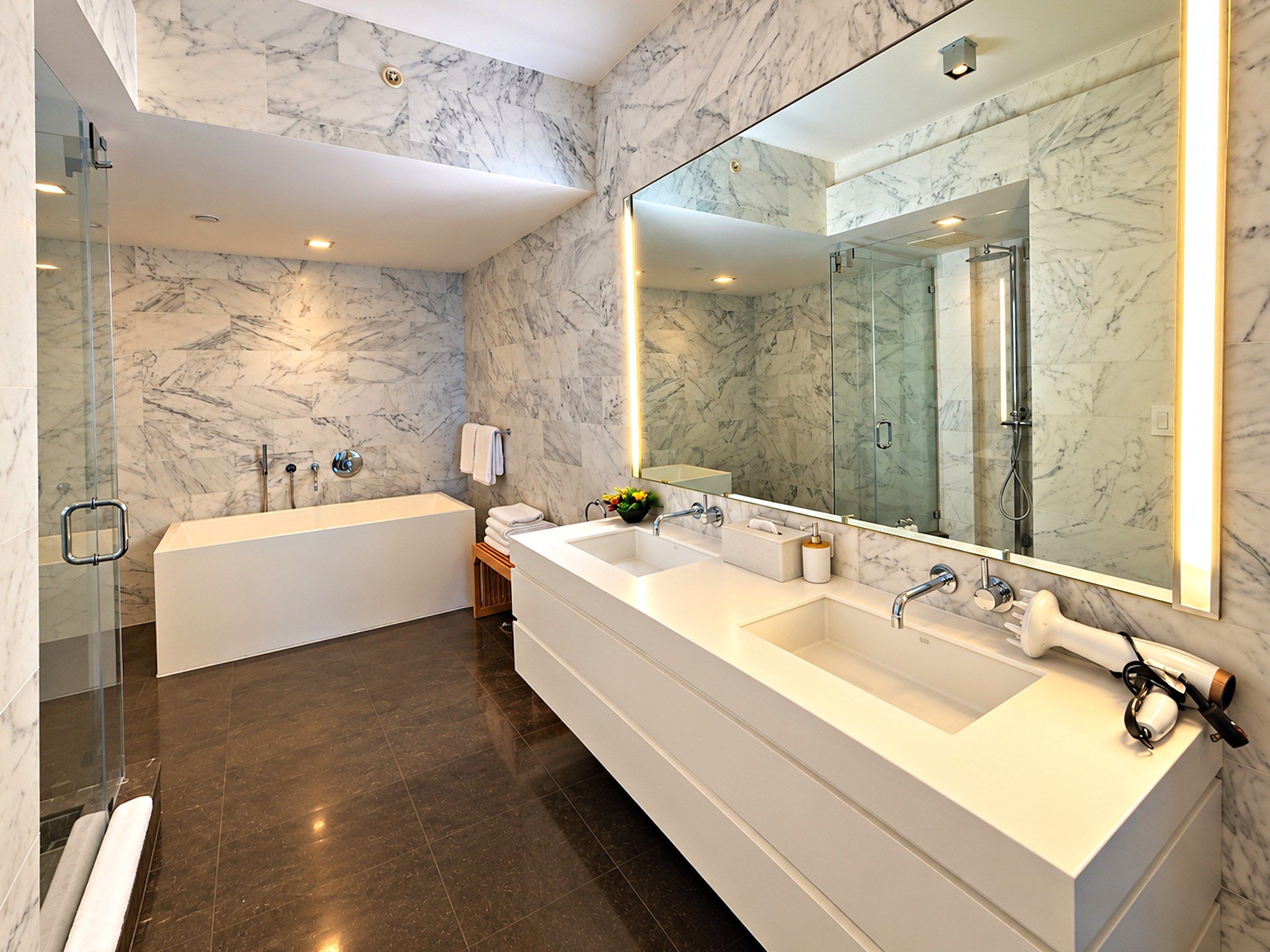 Une salle de bain moderne avec une grande baignoire blanche, un meuble-lavabo à deux vasques et un grand miroir.