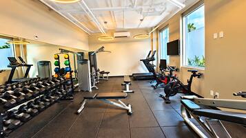 Une salle de sport équipée de matériel d’exercice, d’un tapis de course et d’un rameur.