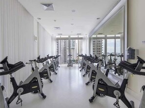 A gym with stationary bikes arranged in rows, large windows, and a high ceiling. - 38th Floor Bay View · 2 King Beds · Icon Brickell (Miami)