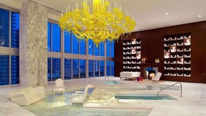 A luxurious indoor pool area with a large chandelier, marble columns, and a view of the cityscape. - Icon Brickell Condo with Bay Views (Miami)