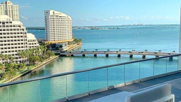 A balcony with a white bench overlooking a marina with boats and a bridge. - Icon Brickell Condo with Bay Views (Miami)